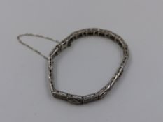 A 14K STAMPED PRECIOUS WHITE METAL AND DIAMOND BRACELET. THE BRACELET MADE OF INDIVIDUAL HINGED