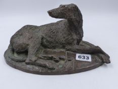 A PATINATED BRONZE FIGURE OF A RECUMBENT IRISH WOLF HOUND. W.23cms.