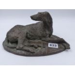 A PATINATED BRONZE FIGURE OF A RECUMBENT IRISH WOLF HOUND. W.23cms.