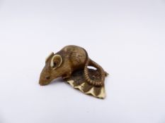 A JAPANESE CARVED IVORY NETSUKE IN THE FORM OF A MOUSE SITTING ON A FAN.