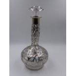 AN ART NOUVEAU GLASS DECANTER WITH OVERLAID WHITE METAL DECORATION. APPROXIMATE HEIGHT 28cms.