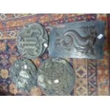 THREE CARVED STONE ROUNDELS AND A REPOUSSE PANEL OF A FISH.