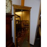 AN ANTIQUE TALL GILT FRAME PIER MIRROR WITH MOULDED SWAG AND URN DECORATION. 189 x 72cms.