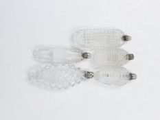 FIVE CLEAR GLASS SCENT BOTTLES WITH CUT DESIGNS AND WHITE METAL STOPPERS.