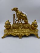 A VICTORIAN STYLE SPELTER AND GILT DECORATED DESK STAND SURMOUNTED WITH A FIGURE OF A SPORTING DOG.