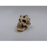 A FINELY CARVED AND INLAID JAPANESE OKIMONO OF A HUMAN SKULL WITH OVERALL DECORATION OF