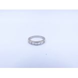 AN 18ct WHITE GOLD EMERALD CUT CHANNEL SET DIAMOND HALF ETERNITY RING. FINGER SIZE L.