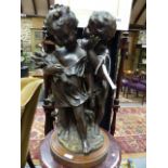 A BRONZE FIGURAL GROUP OF TWO CHILDREN INDISTINCTLY SIGNED ON OAK BASE. OVER ALL H.42cms.