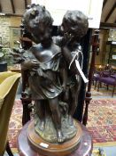 A BRONZE FIGURAL GROUP OF TWO CHILDREN INDISTINCTLY SIGNED ON OAK BASE. OVER ALL H.42cms.