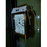A BRASS CASED CARRIAGE CLOCK WITH A WHITE ENAMEL DIAL COMPLETE WITH KEY. H.14cms.