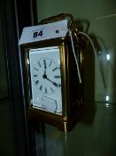 A BRASS CASED CARRIAGE CLOCK WITH A WHITE ENAMEL DIAL COMPLETE WITH KEY. H.14cms.