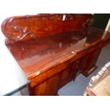 AN EARLY VICTORIAN MAHOGANY SIDEBOARD WITH RAISED CARVED PANEL BACK OVER DRAWERS AND FOUR DOORS ON