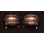 Pair of Victorian salts of circular form raised on hoof feet, the bodies moulded with scrolls,