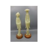 Two oriental green composition figures: master and geisha girl raised on stone plinths, 9 1/2" tall