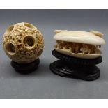 Two items of Chinese ivory both on wooden stands, to include a small puzzle ball, 2" diameter,