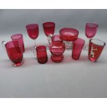 Group of assorted cranberry wares to include a small pedestal bowl, three cranberry jugs, two