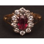Precious metal ruby and diamond cluster ring, the oval cut faceted ruby (7mm x 2.8mm app) claw set