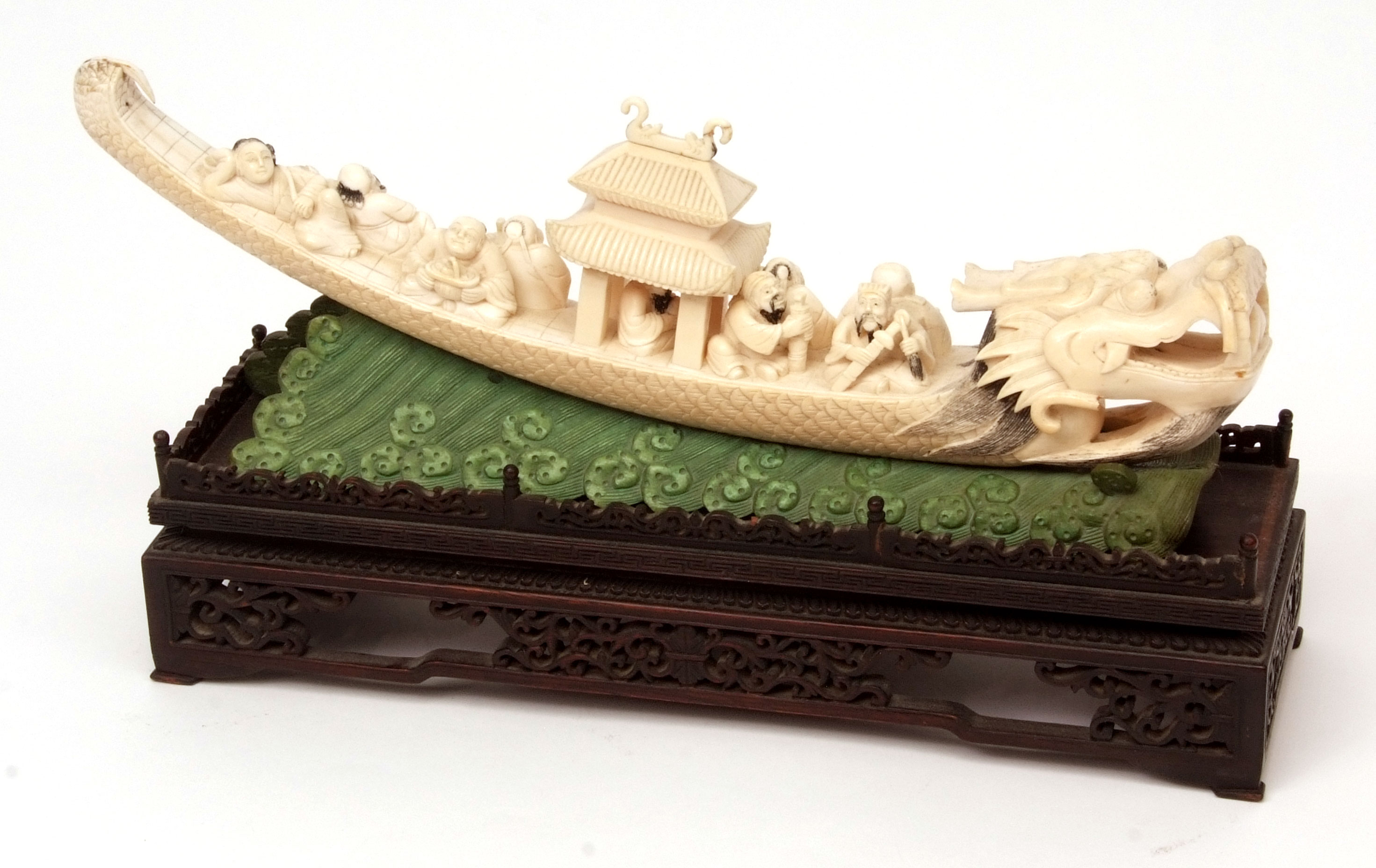 Chinese ivory carving of the lucky gods aboard a dragon pleasure boat set upon a green stained