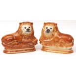 Pair of late Victorian Staffordshire models of reclining lions, each with glass or composition eyes,