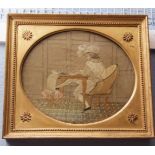 19th century silk/wool work embroidered picture, depicting a young scribe seated at a table with