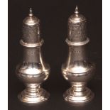 Two George V pepper casters, each of baluster form with pierced and pull-off covers and cast and