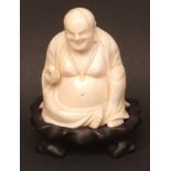 Chinese ivory carving of Budai (also known as Putai), seated, holding a small fruit in his right