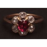 Precious metal ruby and diamond cluster ring, the circular cut facetted ruby surrounded by six mixed