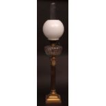 Victorian oil lamp with milk glass shade over a clear glass faceted font and raised on a brass