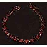 Modern 9ct gold garnet line bracelet, having 20 oval faceted garnets, (claw set), 170mm long