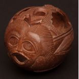 Carved and pierced coconut shell decorated with stylised mask and foliate detail, width 4 1/2 ins