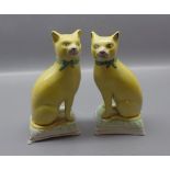 Pair of Staffordshire model cats, seated on cushions with yellow ground with green detailing to