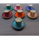 Group of seven various coloured coffee cans with matching saucers and gilded rims