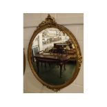 Late 19th century gilt framed oval wall mirror with carved shell top with foliage relief, bevelled