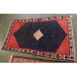 Modern blue and red central diamond lozenge design floor rug with tasselled edge, 44ins x 74ins