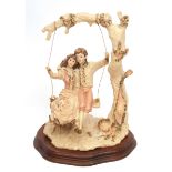 Capo di Monte style large resin group of two lovers on a swing, signed Scaggiari , shaped wooden