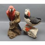 Model of a puffin standing on rocks,and a coloured model of a parrot by Animal Classics Unite