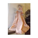 Painted faced doll in a puce silk dress on turned stand with crochet detail, 15ins tall