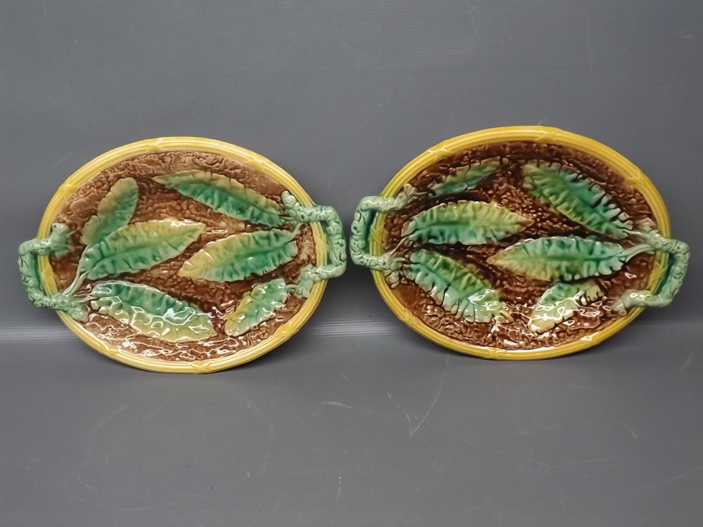 Pair of oval majolica dishes with raised leaf design, side handles, each 12ins x 9ins
