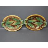 Pair of oval majolica dishes with raised leaf design, side handles, each 12ins x 9ins