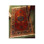 Red ground floor rug with circular blue ground lozenge to centre, among a geometric design, 31 x