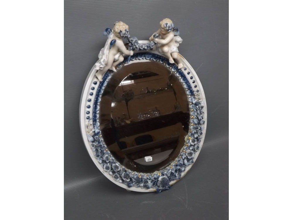 German porcelain floral encrusted oval mirror with two putti mounts to top with garland, decorated