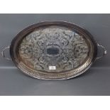 Silver plated oval tray with gallery edge, two handles, engraved detail to the centre, raised on