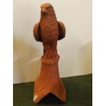 Composition terracotta coloured ridge tile, modelled as an eagle seated on a circular plinth, 9 x