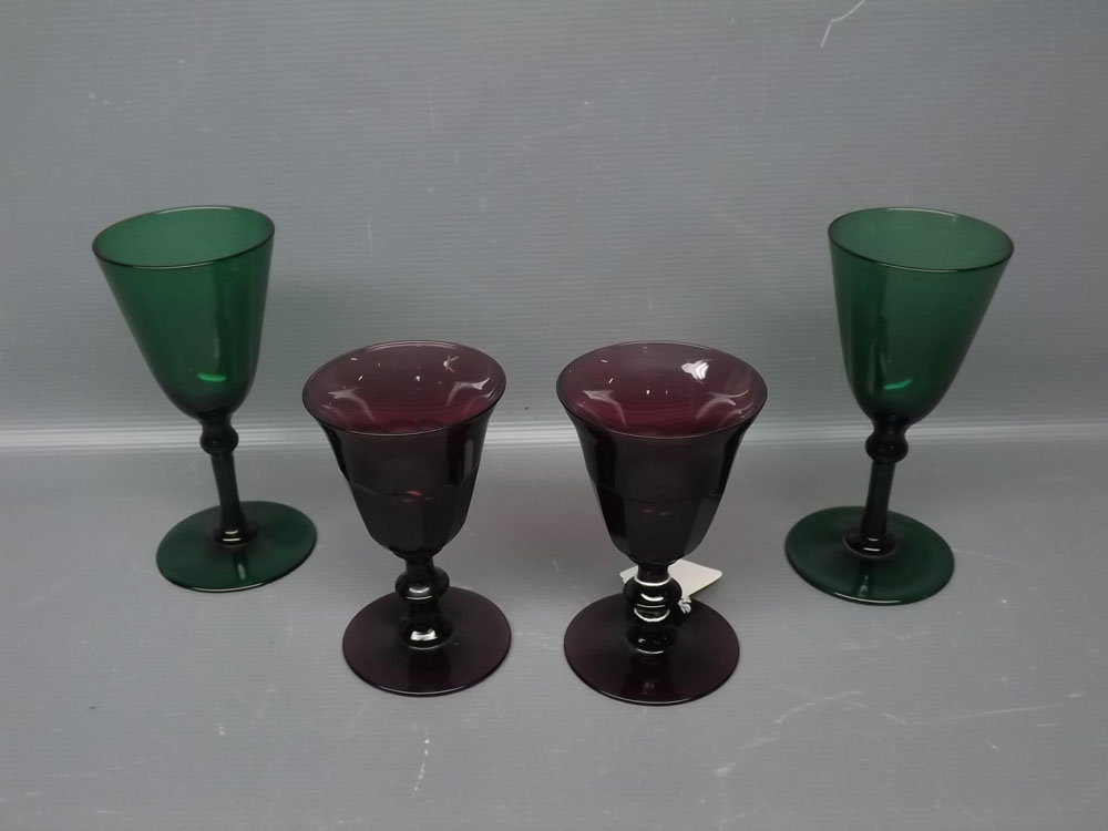 Pair of puce facetted wine glasses together with two green wine glasses with knopped stems and