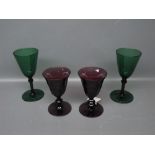 Pair of puce facetted wine glasses together with two green wine glasses with knopped stems and