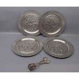 Set of four 20th century German pewter plates, the centres heavily embossed with interior scenes
