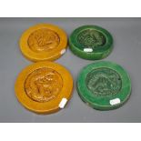 Two green glazed Oriental circular plaques, with dragon decoration, together with two similar yellow