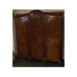 Queen Anne style walnut triple door wardrobe, with panelled doors and arched top, raised on four
