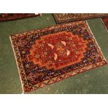 Modern wool carpet with geometric border and blue field with central red lozenge with bird and