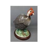 Continental model of a guinea fowl on a foliage base with blue printed mark under (beak a/f), 11 1/2